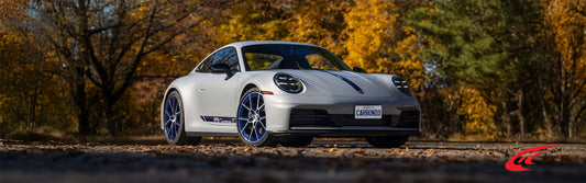 Porsche 911 Carrera T parked on an empty road with autumn leaves fallen on the ground